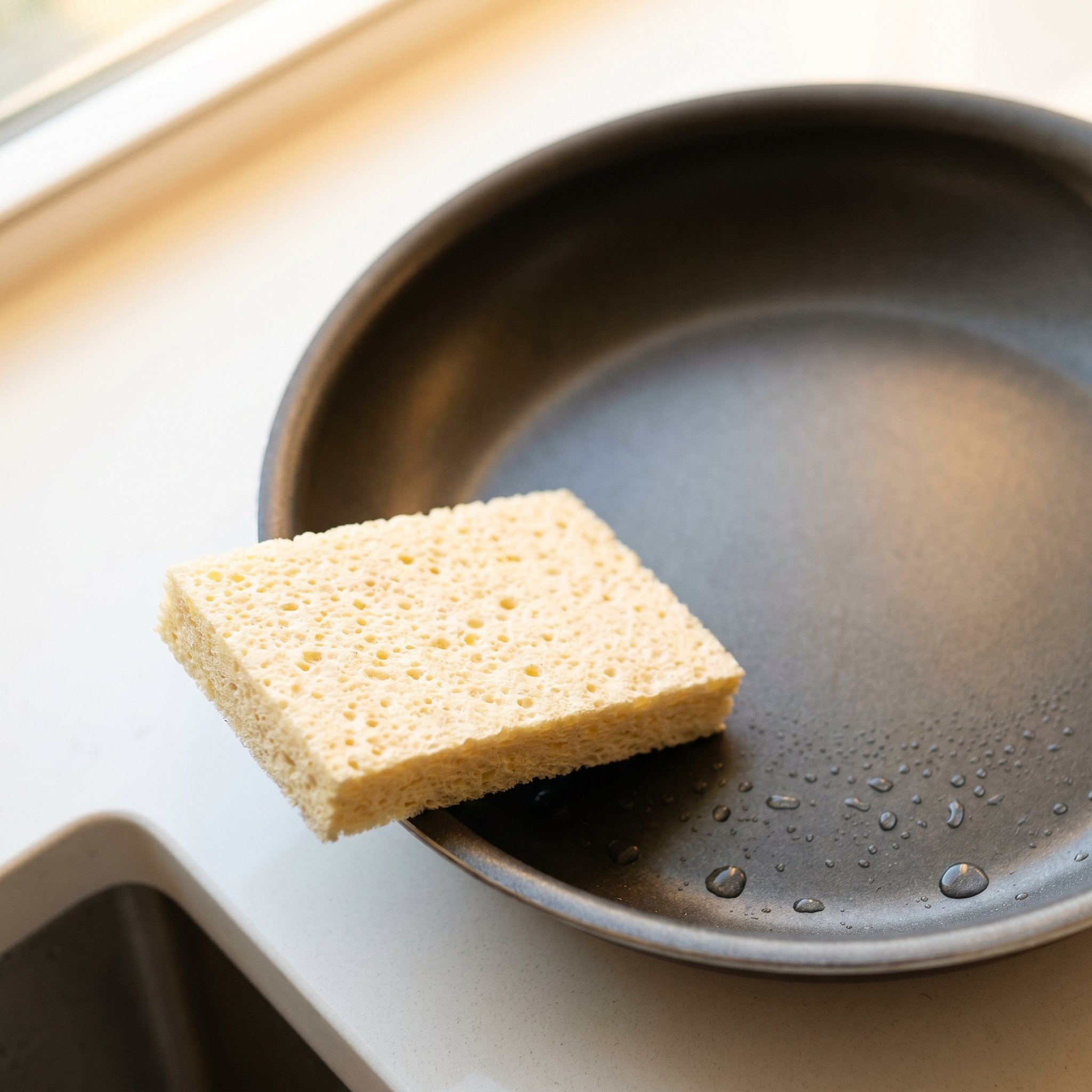 Soft sponge beside a nonstick pan with water droplets, the dishwasher alternative