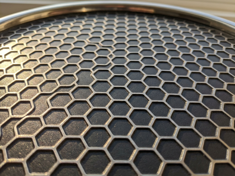 Close-up of hexagonal hybrid cooking surface showing raised stainless steel peaks with dark nonstick valleys