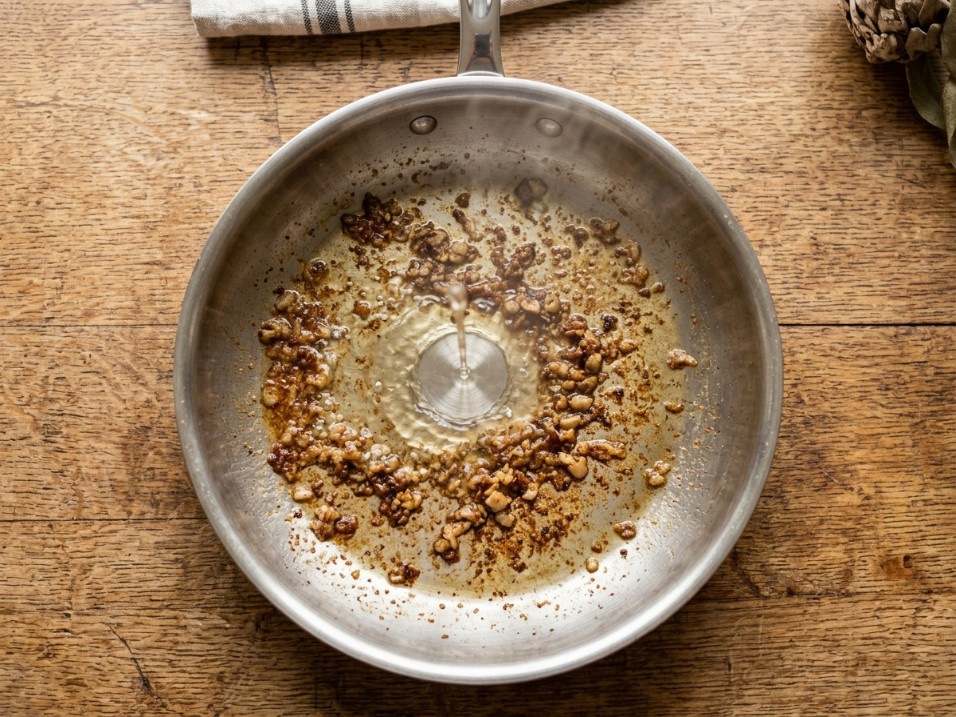 Amazon Basics tri-ply stainless steel fry pan showing the polished cooking surface and riveted handle