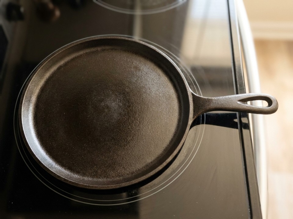 Round cast iron griddle centered on a single glass-top stove element