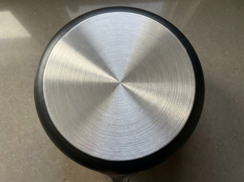 Close-up of a pan base showing faint circular machining marks versus a smooth uniform ceramic coating