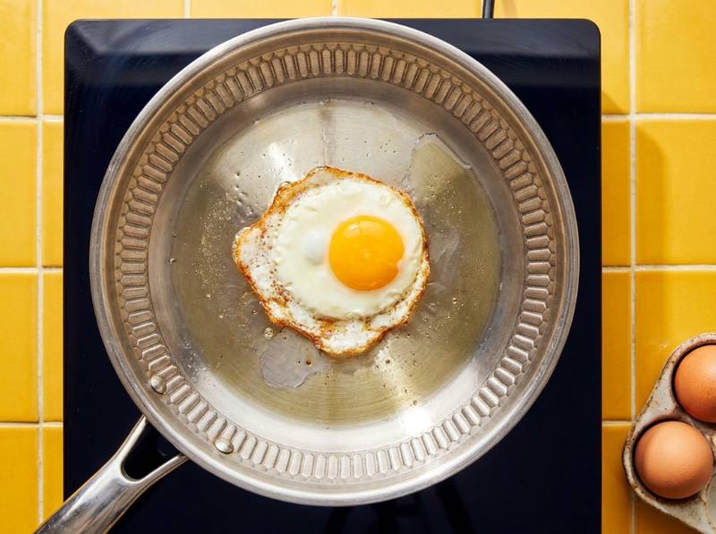 Fried egg cooking in a small pool of oil in a hybrid frying pan on an induction cooktop