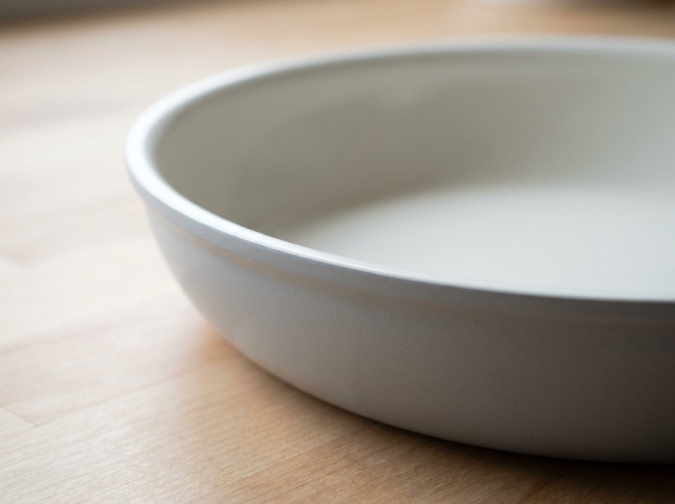 Close-up of a ceramic-coated pan's rolled rim showing the matte exterior coating meeting the pale interior cooking surface
